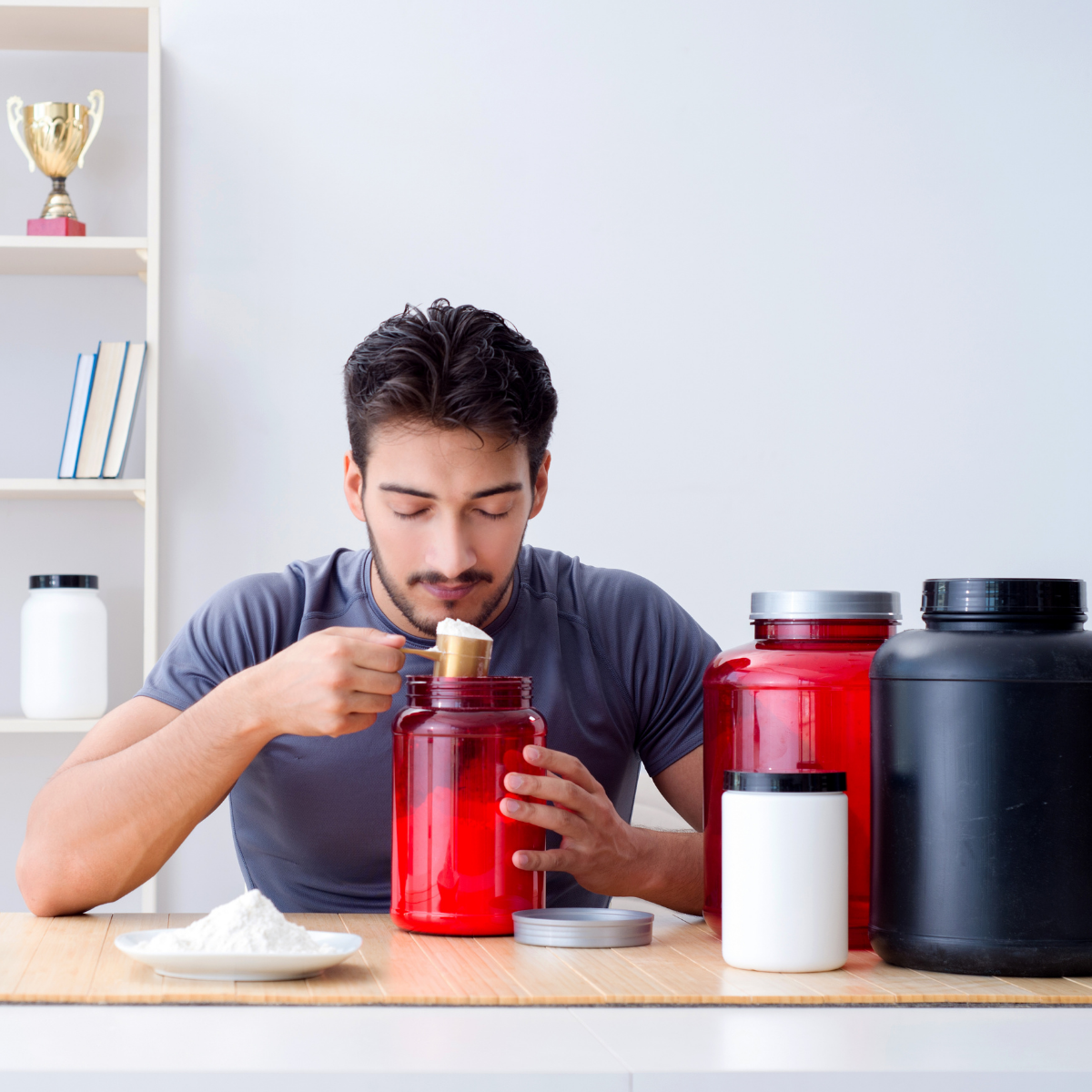 "Mann misst Proteinpulver aus einer großen roten Dose – ideal für Fitness, Muskelaufbau und gesunde Ernährung."