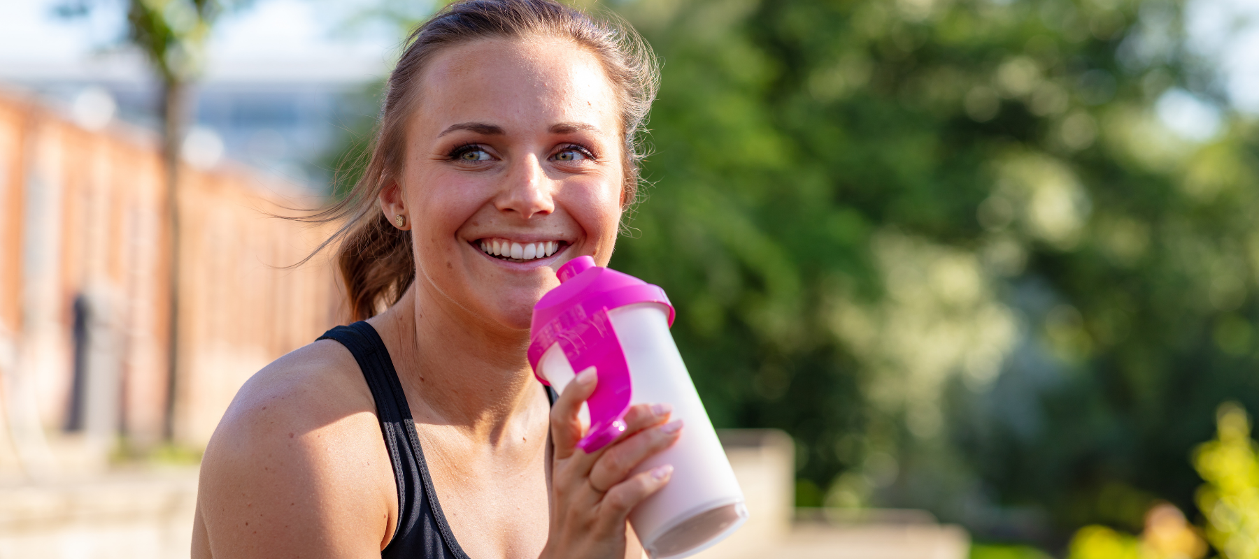 "Sportlerin genießt einen leckeren Shake nach dem Training – perfekt für eine proteinreiche Regeneration mit NOM Basic."