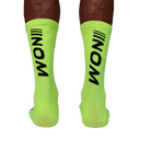 "Neongrüne NOM Sportsocken mit schwarzem Logo, getragen von einem Sportler."