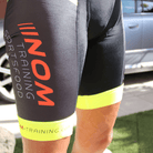 "Pro Race Radhose von NOM Training: Schwarzes Design mit auffälligen gelben Bündchen und rotem Markenlogo."